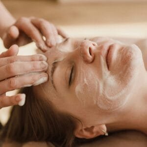 Una mujer recibiendo limpieza facial con una máscara de skincare